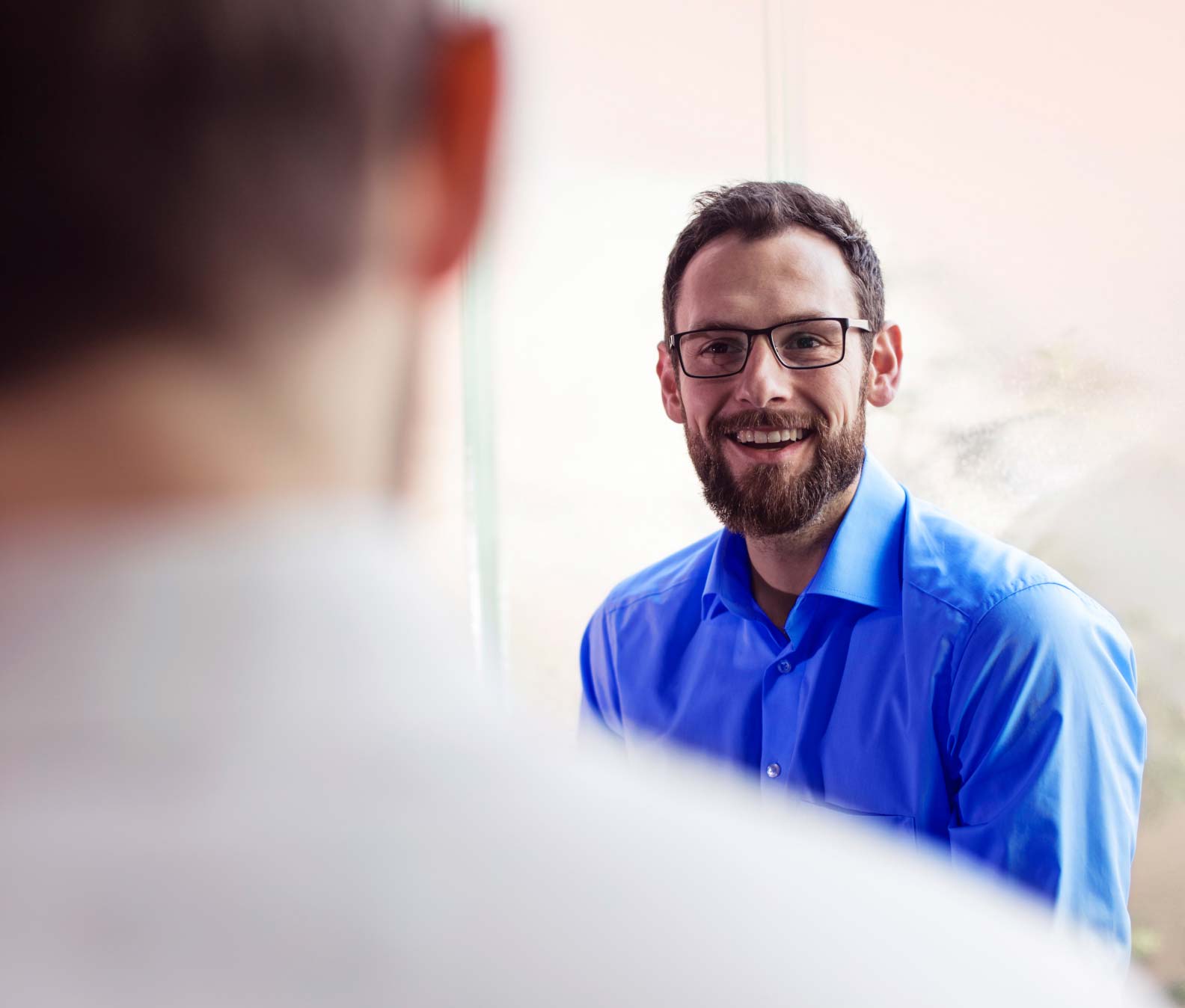 Man in blue shirt smiling at another man