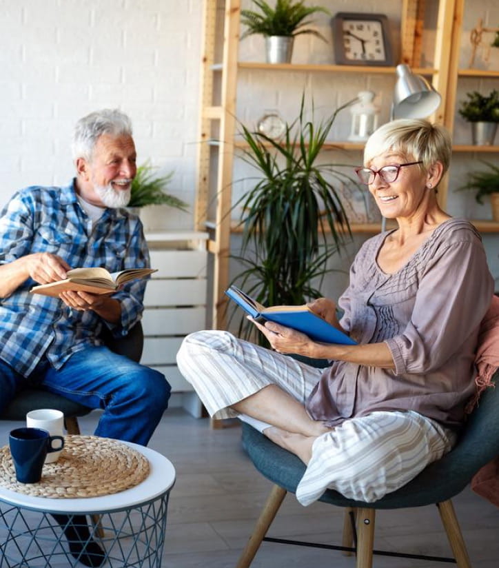 Older woman reading a book to husband in living-room