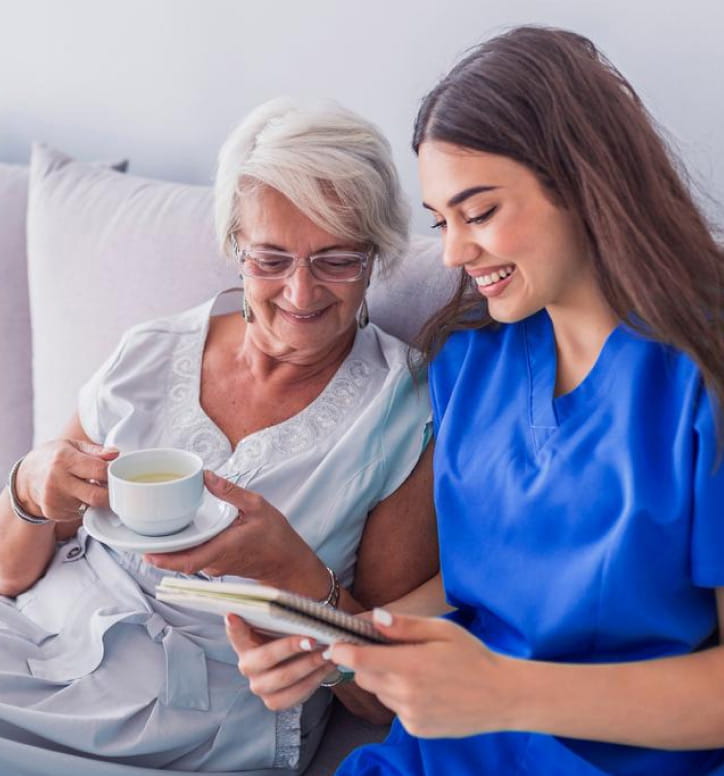 Young female nurse with elderly lady on couch