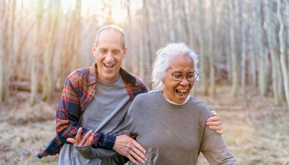 Laughing senior couple going on a walk in the woods