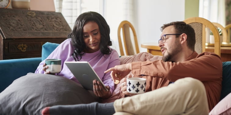 Couple sitting on couch looking at ipad